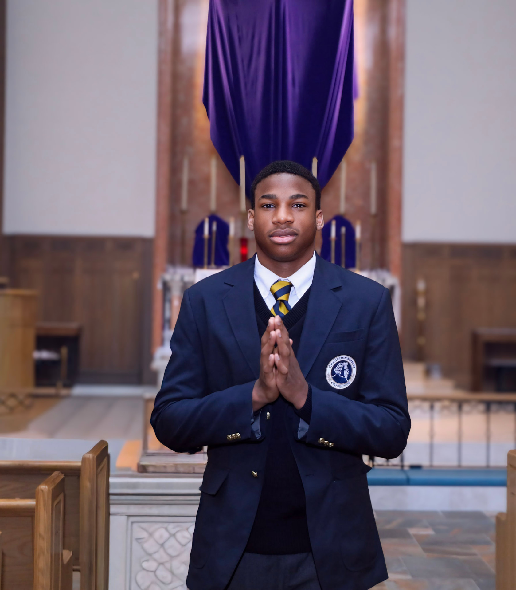 A Chesterton Academy student in uniform praying in the chapel